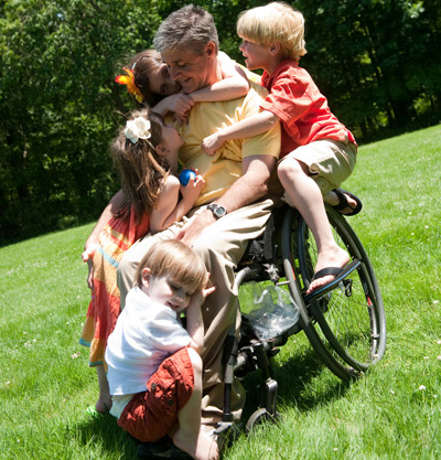 children hugging dad wheelchair